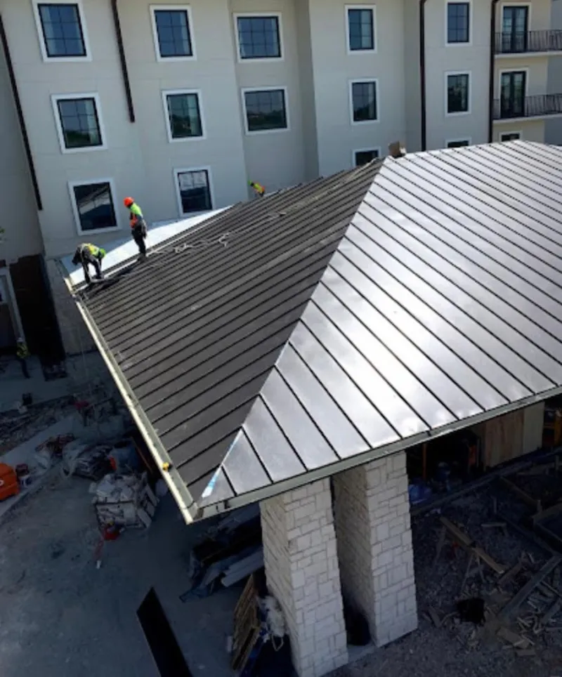 Crew installing standing seam metal roof panels on a commercial project in Bloomingdale